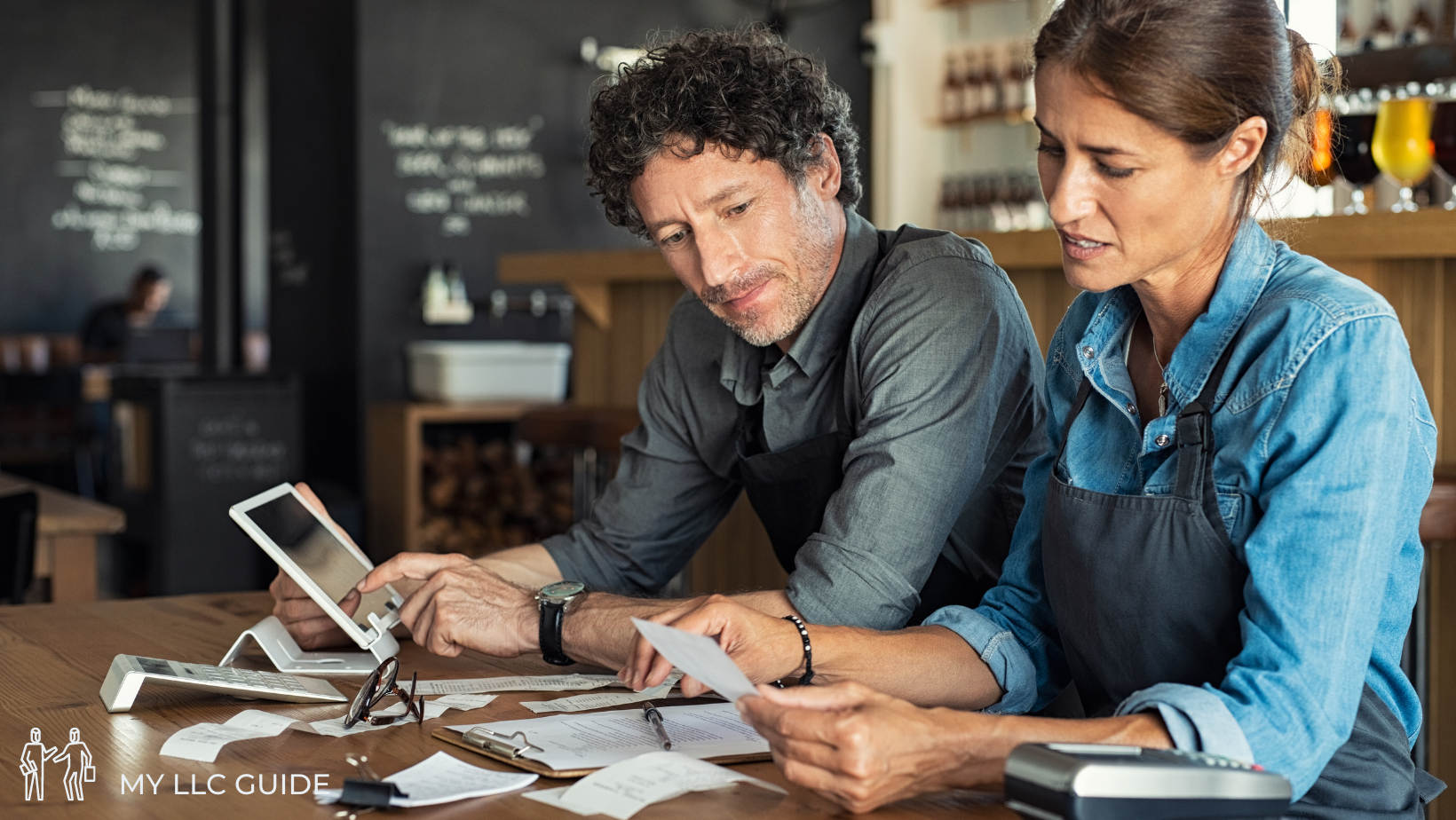 man and woman writing an LLC articles of organization on laptop