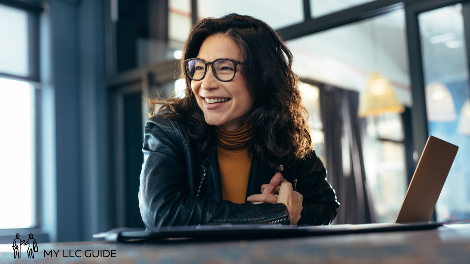 woman in an office working on a laptop and wearing glasses