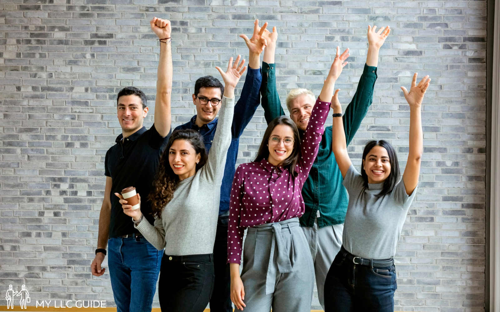 a team of office workers cheering with hands in the air